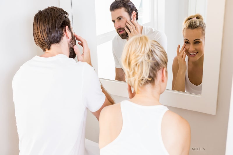 Attractive couple examining their faces in the mirror