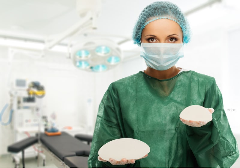 Surgeon holds small and large breast implants.