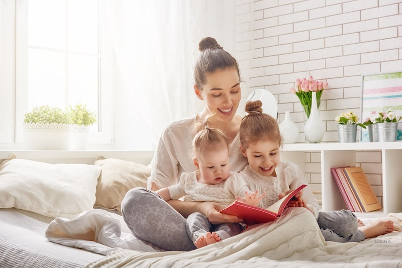 Happy mom reading a book to her two young children